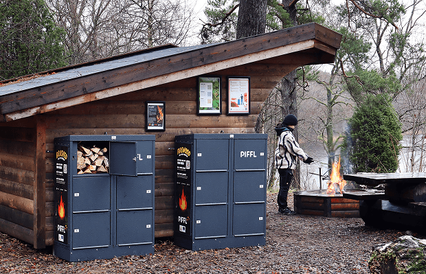 Vindskydd i skogen med två Piffl Brasved boxar och en tjej som värmer sig vid elden.